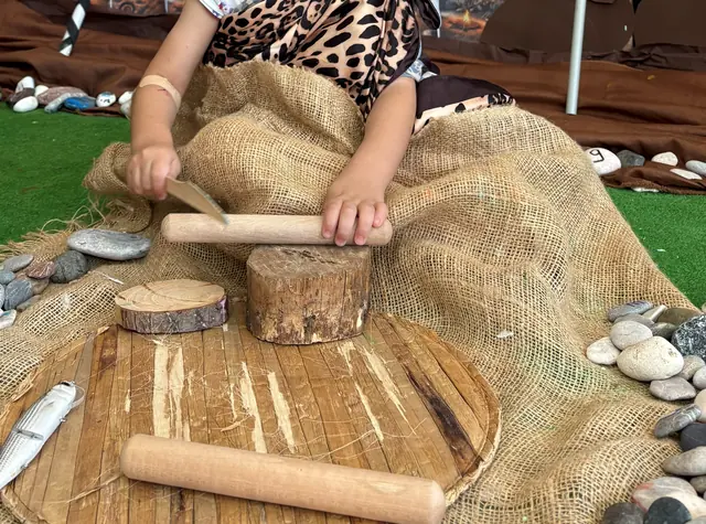 Havanla çalışan çocuk elleri, çevresinde taşlar ve ahşap kütükler